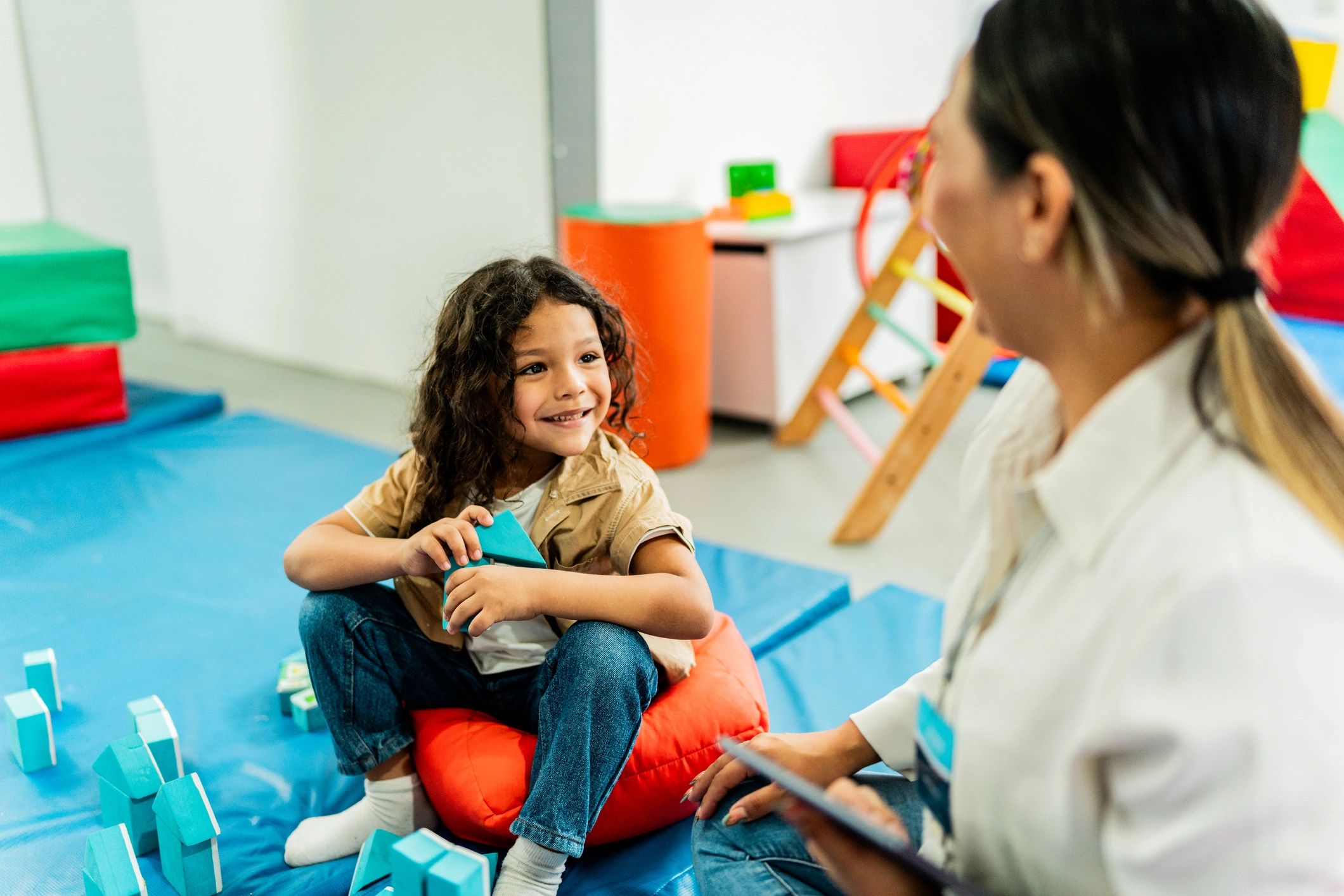 Child talking with therapist while playing with blocks in a therapy clinic